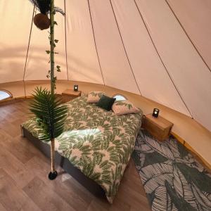 a bedroom with a bed and a plant in a tent at Le Tipi Tropical au bord de la rivière in Mios
