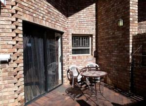 a patio with a table and chairs next to a brick building at de Klerens Gems Topaz Self Catering Studio in Clarens