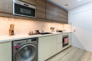 a kitchen with a washing machine and a microwave at Beach and City Lifestyle in 2 Bed Holiday Home JBR in Dubai