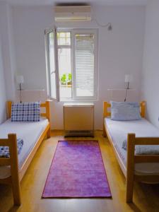 2 camas en una habitación con ventana y alfombra en Jasmin en Belgrado