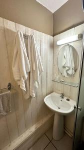ein Badezimmer mit einem Waschbecken, einem Spiegel und Handtüchern in der Unterkunft Hôtel Le Valéran in Ligny-en-Barrois