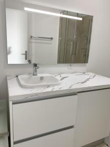 Baño blanco con lavabo y espejo en Studio front de mer, 30M2 Piscine & Mer, en Cannes