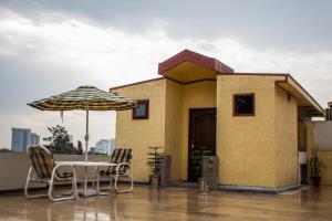 een patio met een tafel en stoelen en een parasol bij S Chalet Islamabad in Islamabad