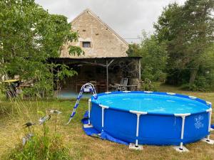 a blue tub in a yard next to a house at Maison L’Atelier in Thollet