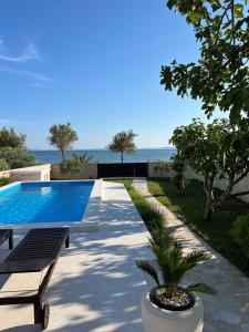 a swimming pool with a bench and the ocean at Holiday House Laura in Vir