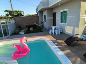 una piscina con un cisne rosa en el agua en Casa alguns passos do mar com piscina e SPA Aquecido, en Guaratuba