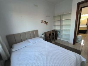 a bedroom with a white bed and a closet at Casa alguns passos do mar com piscina e SPA Aquecido in Guaratuba