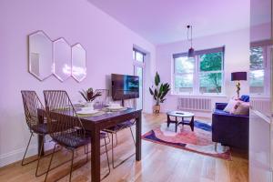 uma sala de estar com uma mesa e cadeiras e um sofá em Artsy Serviced Apartments - Ealing em Londres
