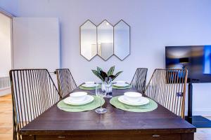 a wooden table with plates and glasses on it at Artsy Serviced Apartments - Ealing in London