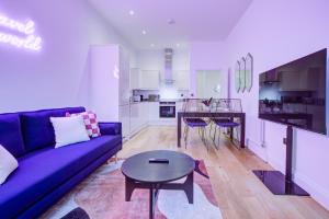 a living room with a purple couch and a table at Artsy Serviced Apartments - Ealing in London