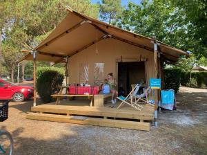 Eine Frau, die in einem Zelt mit einem Tisch sitzt. in der Unterkunft Village Seasonova Bassin d'Arcachon in Audenge