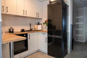 a kitchen with white cabinets and a black refrigerator at Apartament Lawenda in Ciechocinek