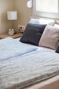 Una cama con sábanas azules y blancas y una ventana en Balatonic Orange en Zamárdi