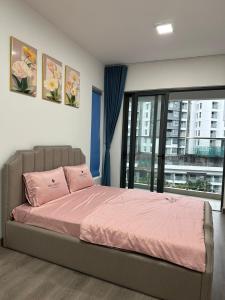 um quarto com uma cama com lençóis cor-de-rosa e uma janela em Căn hộ Vip 3 Phòng khu Diamond Celadon, ngay Aeon mall Tân Phú em Ho Chi Minh