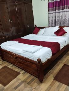 a bedroom with a large bed with white and red pillows at SLS HOMESTAY - Luxury AC Service Apartments 1BHK, 2BHK, 3BHK - Direct Flyover to Alipiri Tirumala Gate - Walk to PS4 Pure Veg Restaurants, Supermarkets - Near to National Highway & Padmavathi Amma Temple - Modular Kitchen, Living room -Free Superfast Wifi in Tirupati