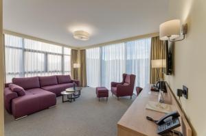 uma sala de estar com um sofá roxo e cadeiras em Hotel Siesta em Užice