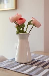 a white vase with pink flowers in it on a table at Casa Mia - Apartments & Suites in Koper