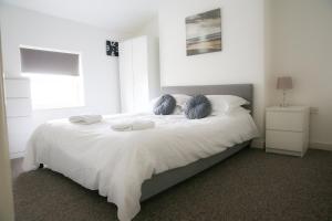 a bedroom with a white bed with two blue pillows at Contemporary 2 Floor Flat with Sea Views! in Lowestoft