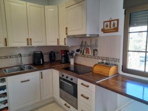 a kitchen with white cabinets and a sink at 200 m playa, WiFi, TV SAT, BBQ in Pilar de la Horadada