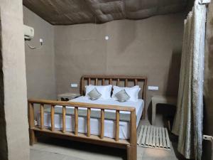 a bedroom with a bed with white sheets and pillows at Virsaa - The Captain's Mud Retreat in Sirhind