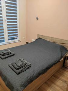 a bedroom with a bed with black sheets and a window at Cozy New Apt - Уютен апартамент in Blagoevgrad