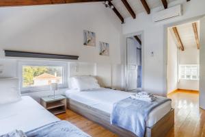 2 Betten in einem Schlafzimmer mit weißen Wänden und Holzböden in der Unterkunft Villa Pavlos in Skopelos