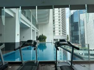 einen Fitnessraum im Innenbereich mit einem Pool in einem Gebäude in der Unterkunft One Bukit Ceylon by Home Suites in Kuala Lumpur