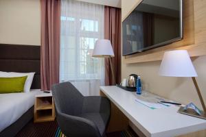 a hotel room with a bed and a desk with a chair at Stay inn Hotel Gdańsk in Gdańsk