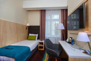 a hotel room with a bed and a desk and a room at Stay inn Hotel Gdańsk in Gdańsk