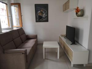 a living room with a couch and a tv at Casa Carmen 1 in Cudillero