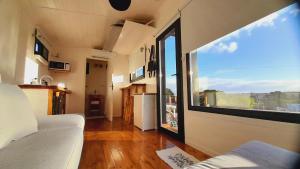 Cette chambre située dans une petite maison dispose d'une grande fenêtre. dans l'établissement CheTiny Sunset - Tiny House en Sierra de los Padres, à Sierra de los Padres