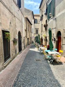 an alley with tables and chairs on a street at All’ombra del museo in Tarquinia