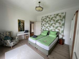 - une chambre avec un lit doté d'oreillers verts et d'une chaise dans l'établissement "Zur Erholung" in Jugendstilvilla Sonnenschein, à Stolberg