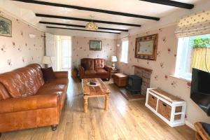 a living room with a leather couch and a tv at Angel Valley Cottage in Brockenhurst