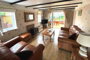 a living room with leather couches and a television at Angel Valley Cottage in Brockenhurst