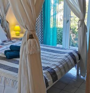 1 dormitorio con 1 cama con cortinas y ventana en Cosy & Calme en Le Tampon