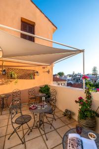 a patio with chairs and tables and an umbrella at Santa Elena Boutique Rooms in Chania