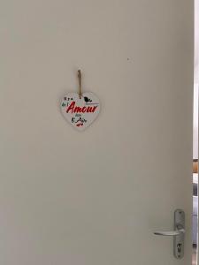 ein herzförmiges Schild, das an einer weißen Wand hängt in der Unterkunft Il y a de l'amour dans l'air - studio lit king size in Arromanches-les-Bains