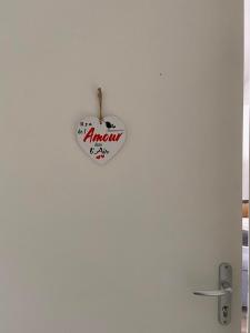 a heart shaped sign hanging on a white wall at Il y a de l'amour dans l'air - studio lit king size in Arromanches-les-Bains