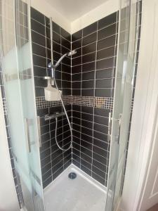 eine Dusche im Bad mit schwarzen Fliesen in der Unterkunft Il y a de l'amour dans l'air - studio lit king size in Arromanches-les-Bains