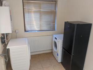 a laundry room with a refrigerator and a washing machine at Edgefield House in Barking