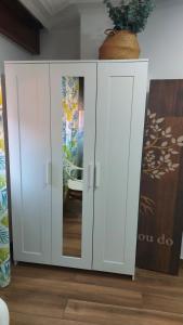 a white cabinet with doors and a plant on top at Apartamento Céntrico cerca de la playa in Bueu
