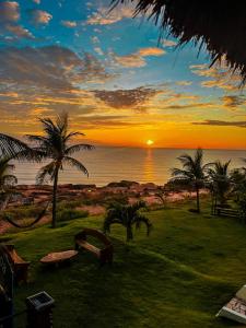 una puesta de sol sobre el océano con palmeras en un campo en Raio de Sol Residence, en Canoa Quebrada