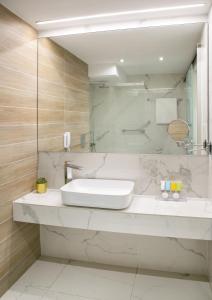 a white bathroom with a sink and a mirror at Cleopatra Hotel in Nicosia