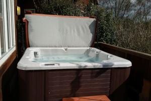 a bath tub sitting in front of a window at Luxury Peak District lodge, hot tub, log burner, nr lake in Rudyard