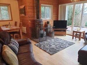 sala de estar con sofá y chimenea en Luxury Peak District lodge, hot tub, log burner, nr lake, en Rudyard