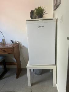 a white refrigerator next to a desk with a plant on top at Centrally Located Private Rooms in Heraklio