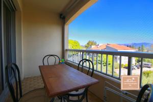 una mesa de madera y sillas en un balcón con vistas en Le Zenith en Saint-Mandrier-sur-Mer