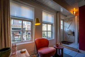 a living room with a chair and two windows at CityCottage Alkmaar in Alkmaar