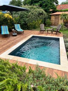 a swimming pool on a deck with two chairs and an umbrella at Les Suites d'Aliénor, Suite Cosy in Pessac